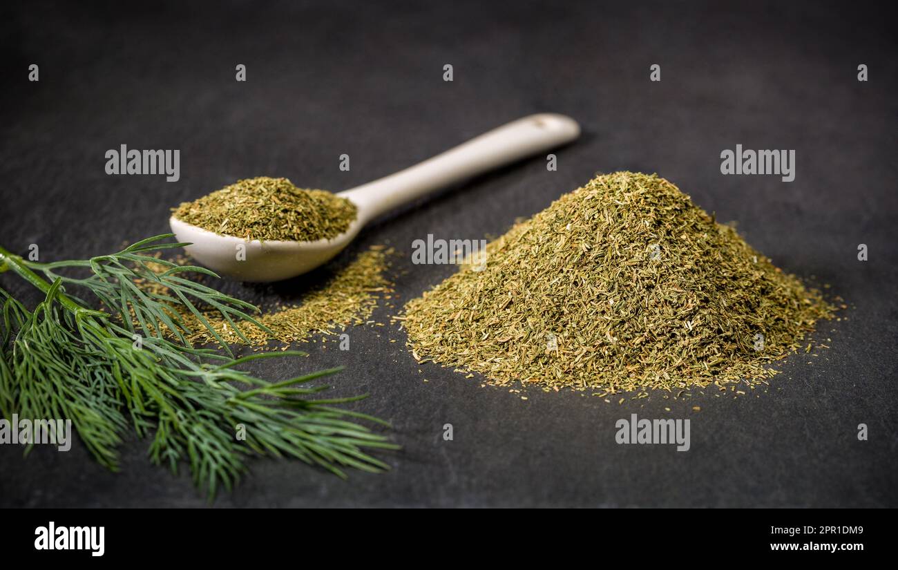 Aneto di spezie aromatiche. Cucchiaio e cumulo di spezie di aneto essiccate e fresche macinate. Ingredienti della ricetta. Foto Stock