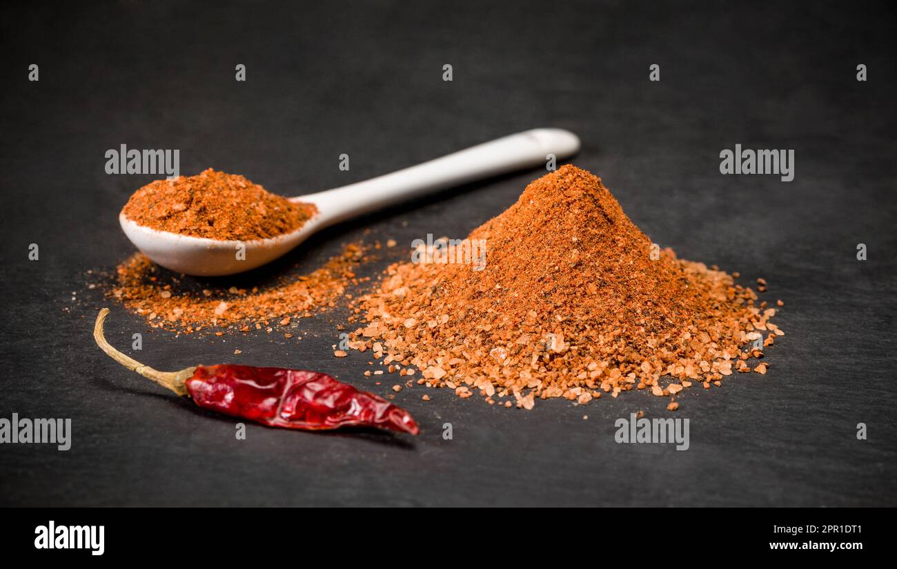 Peperoncino rosso per ricette. Un cucchiaio e un mucchio di pepe in polvere caldo. Spezie macinate. Foto Stock