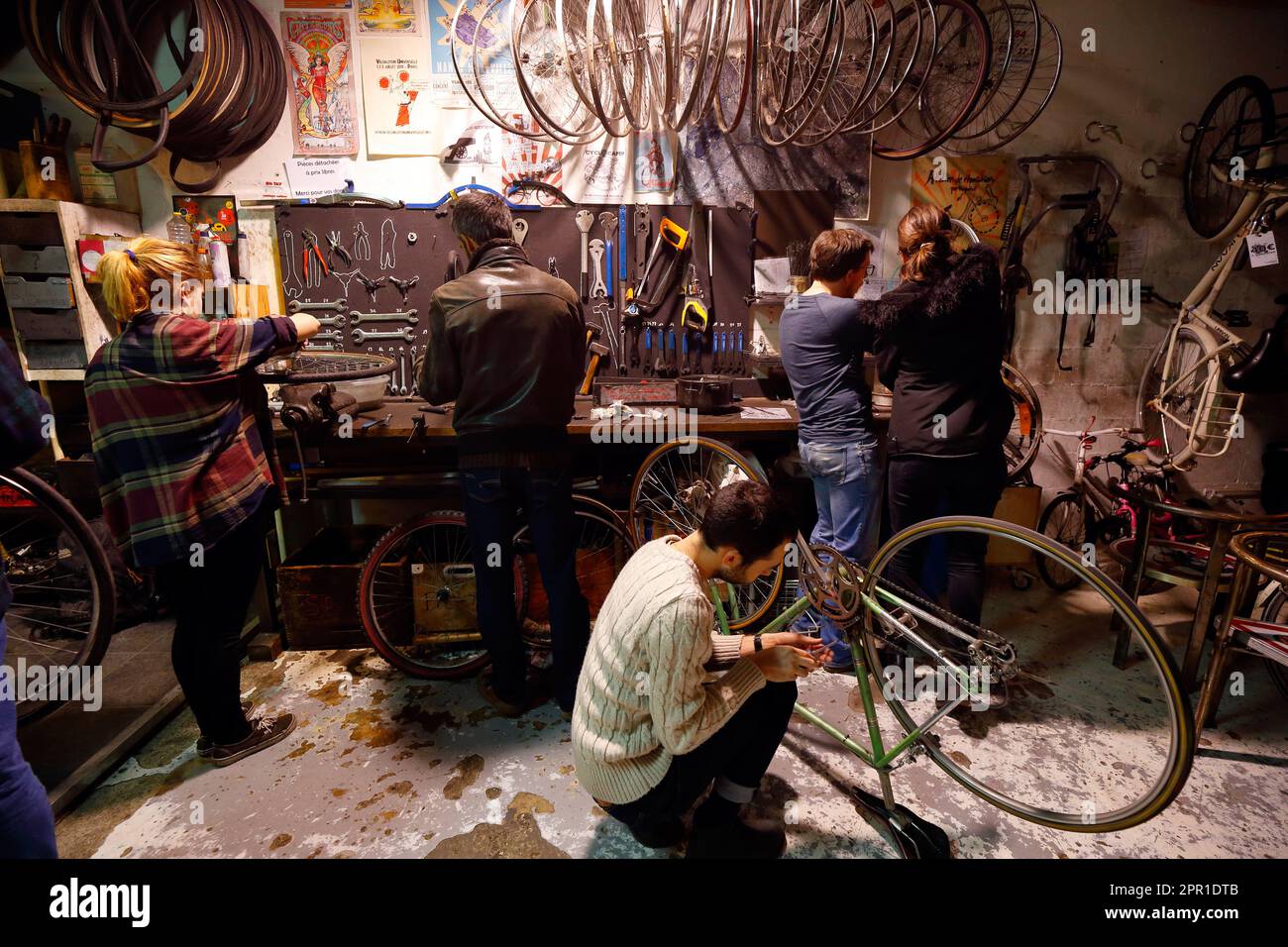 Persone che lavorano su biciclette a la Cyclofficines, 15 Rue Pierre Bonnard, una cooperativa di auto-riparazione a basso costo in bicicletta 20e Arr, Parigi, Francia. Foto Stock