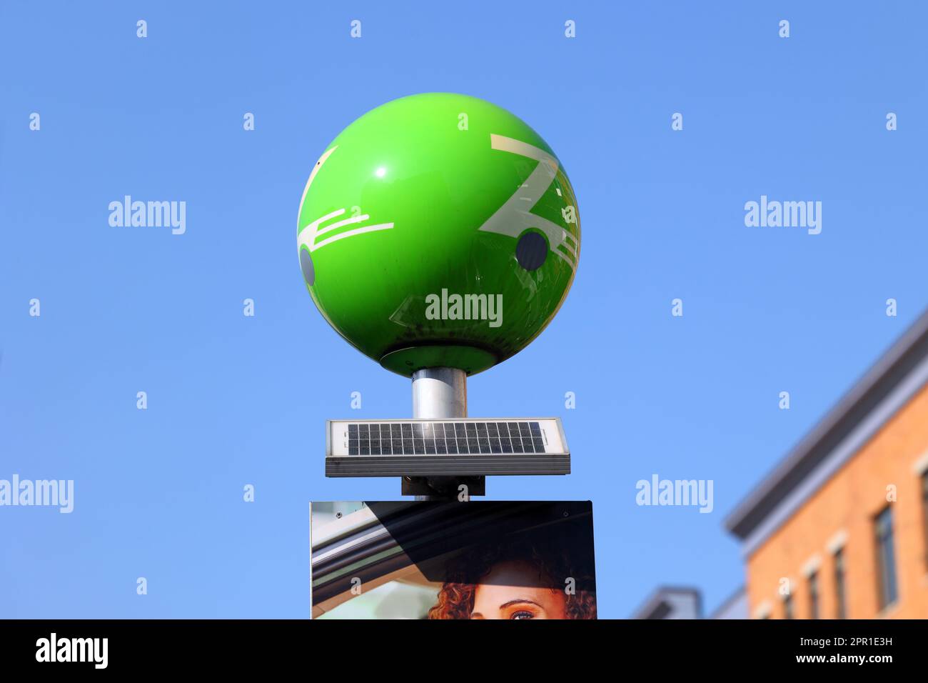 Un cartello solare illuminato che fa pubblicità a Zipcar. La segnaletica solare è costituita da led alimentati a energia solare in un globo verde con pubblicità sulla parte superiore di un palo. Foto Stock