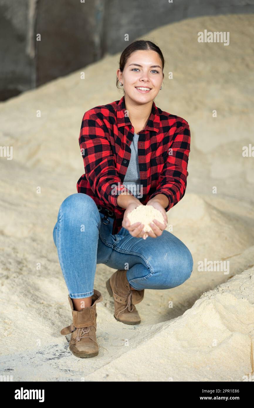 Donna agronomo positiva che squatting a mazzo di farina di mais Foto Stock