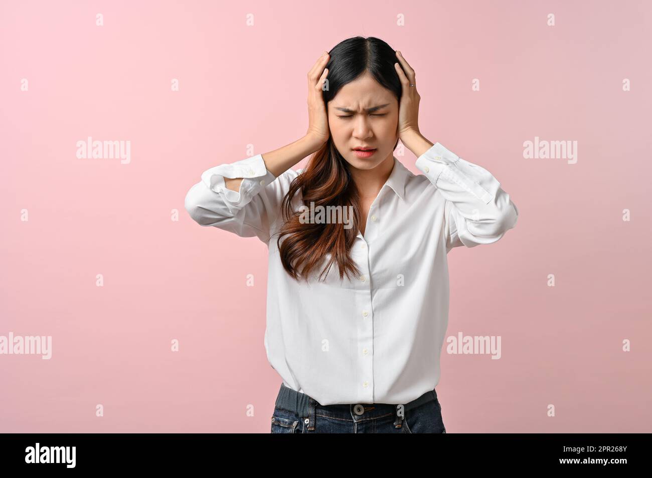 Turbato asiatico donna sensazione di malessere, avendo un mal di testa su sfondo rosa isolato. Foto Stock