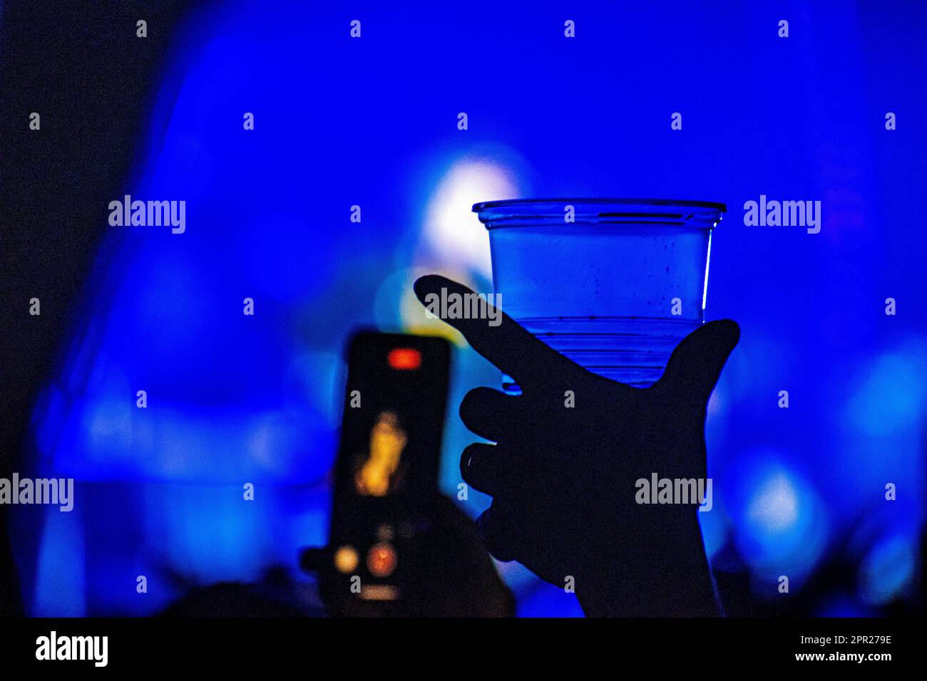 A mano con una tazza di birra di plastica durante un concerto Foto Stock