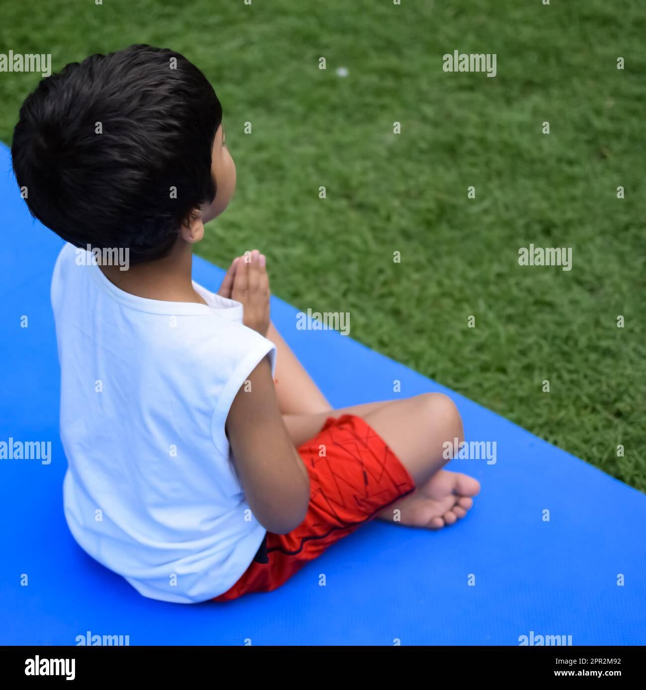 Asian Smart Kid fare yoga posa nel parco sociale all'aperto, la posa yoga dei bambini. Il ragazzino che fa yoga e meditazione. Foto Stock