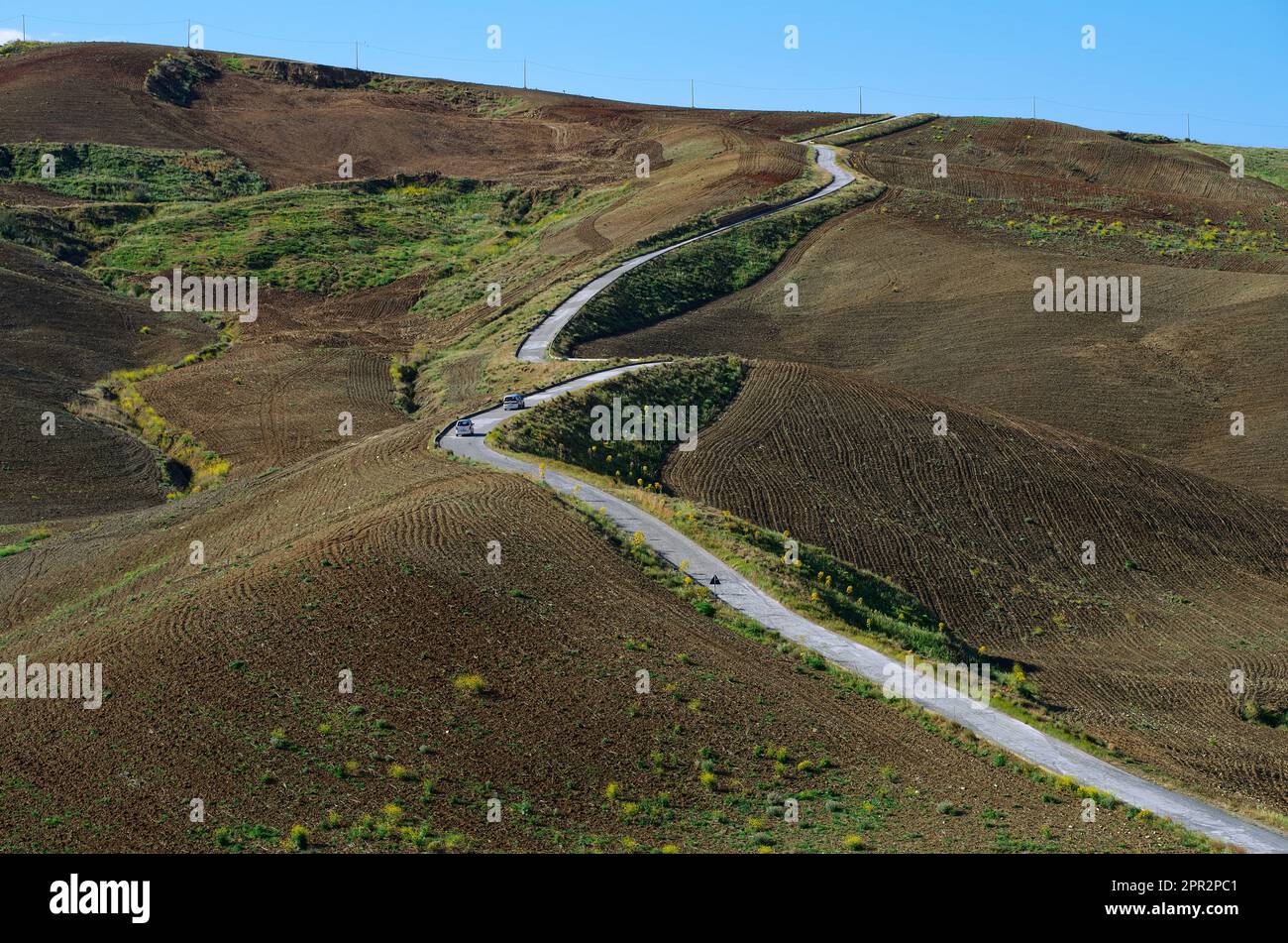 Strada tortuosa attraverso colline di terra arata in Sicilia, Italia Foto Stock