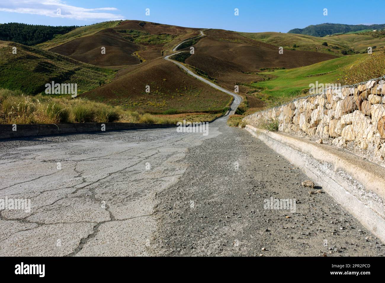 Strada sterrata attraverso colline di terra rossa in Sicilia, Italia (strada) Foto Stock