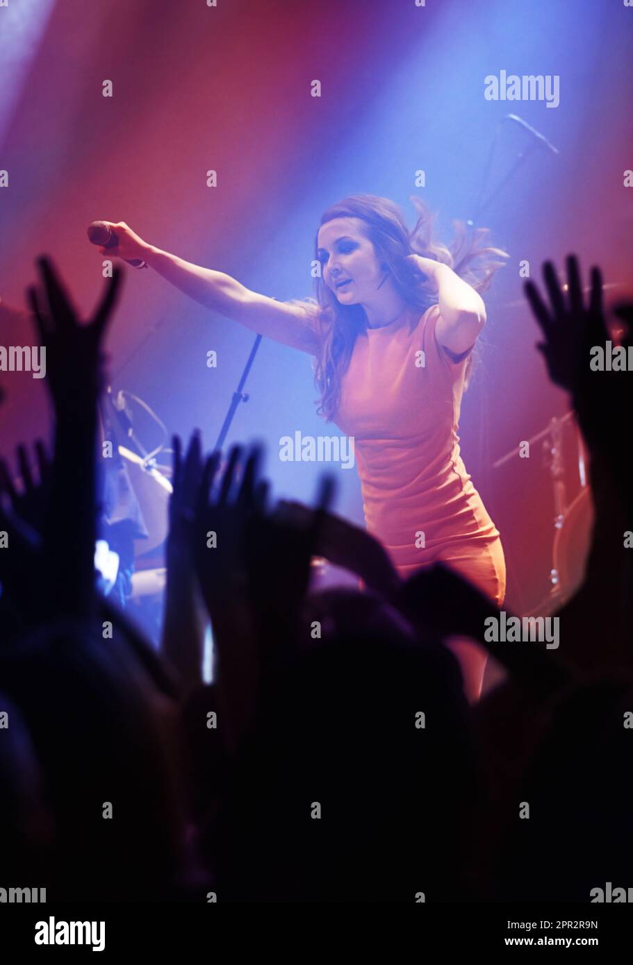 Persone mani, cantante donna e concerto durante lo spettacolo notturno, cantando e gen z in luci, celebrazione o saluti. Musicista persona sul palco e. Foto Stock