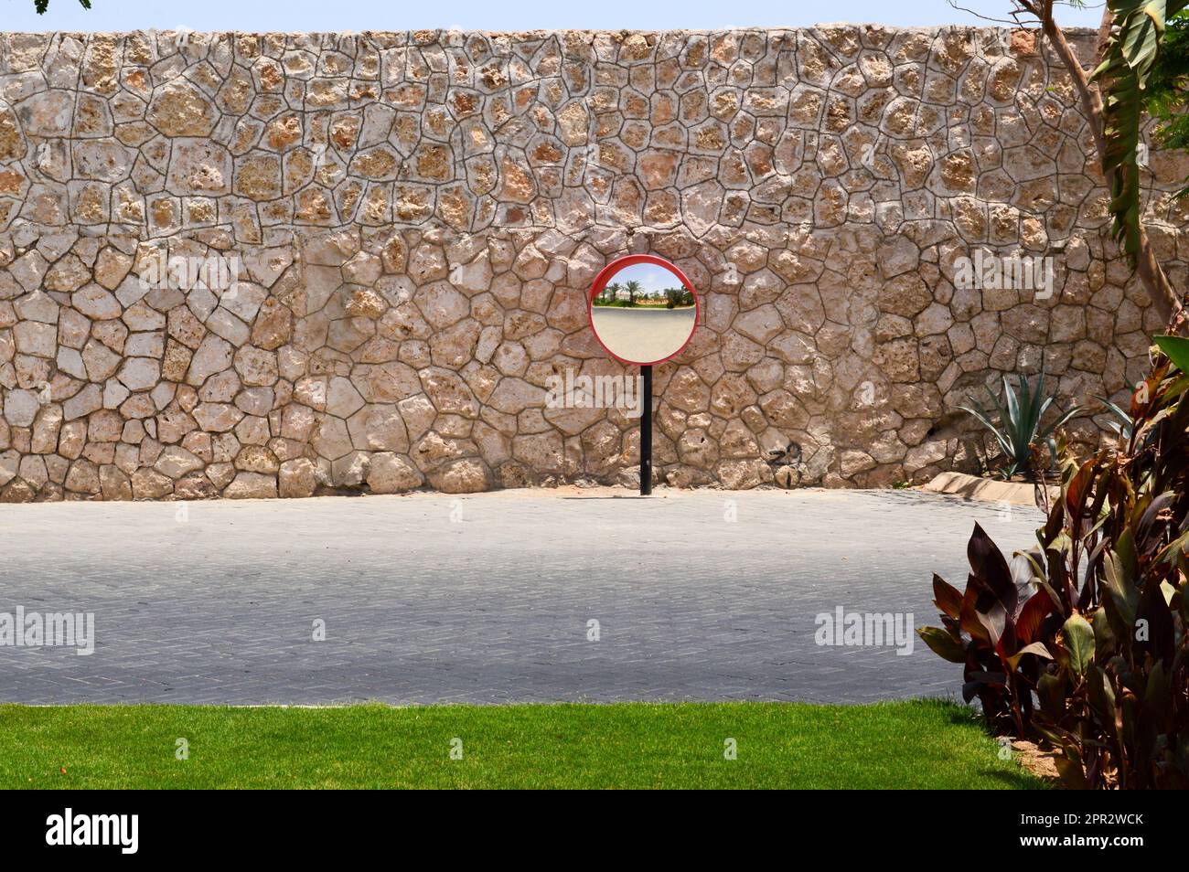 Specchio rotondo sullo sfondo del vecchio muro di pietra e della strada. Foto Stock