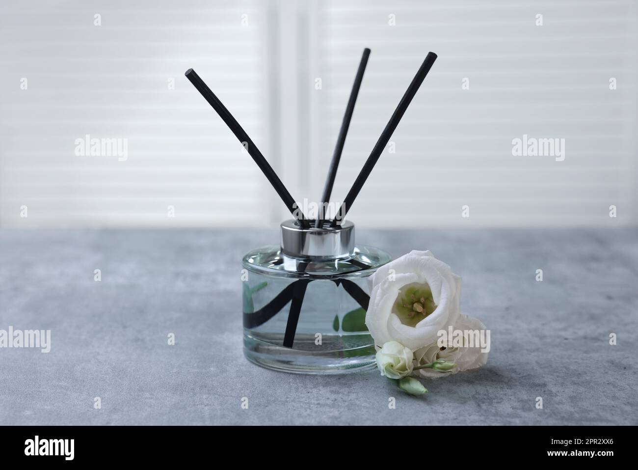 Diffusore a lamelle e fiori di eustoma su tavolo in marmo grigio Foto Stock