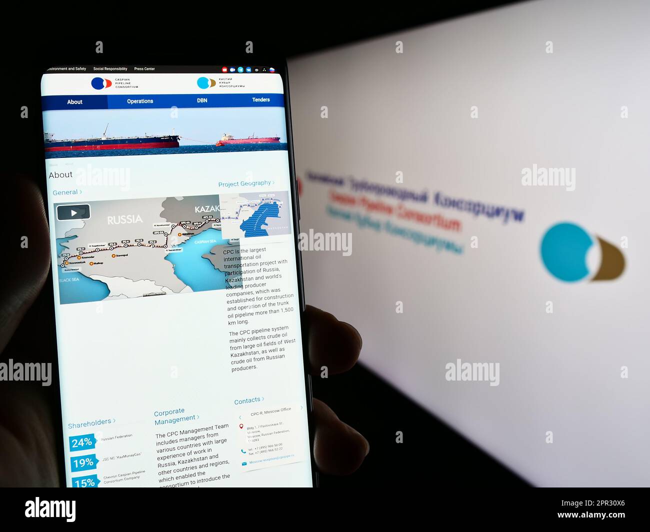 Persona che tiene uno smartphone con il sito Web del CPC (Caspio Pipeline Consortium) sullo schermo davanti al logo. Messa a fuoco al centro del display del telefono. Foto Stock