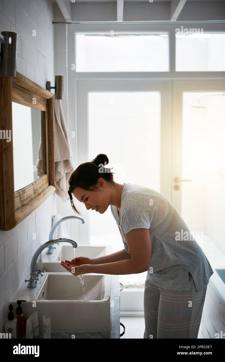 Thatll svegliarti a destra. una giovane donna attraente che si lava in bagno. Foto Stock