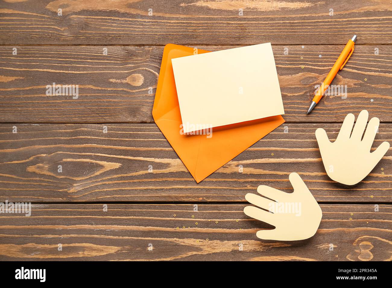 Busta con bigliettino vuoto e palme di carta su sfondo di legno. Festa dell'amicizia Foto Stock