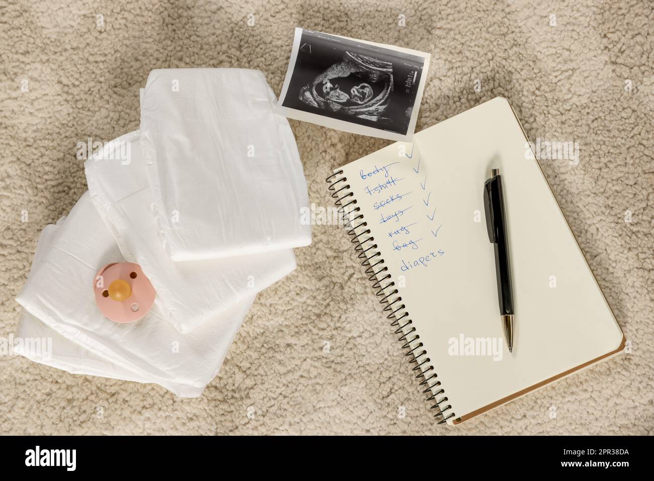 Composizione a posa piatta con articoli per bambini, lista e scansione a ultrasuoni su tappeto beige Foto Stock