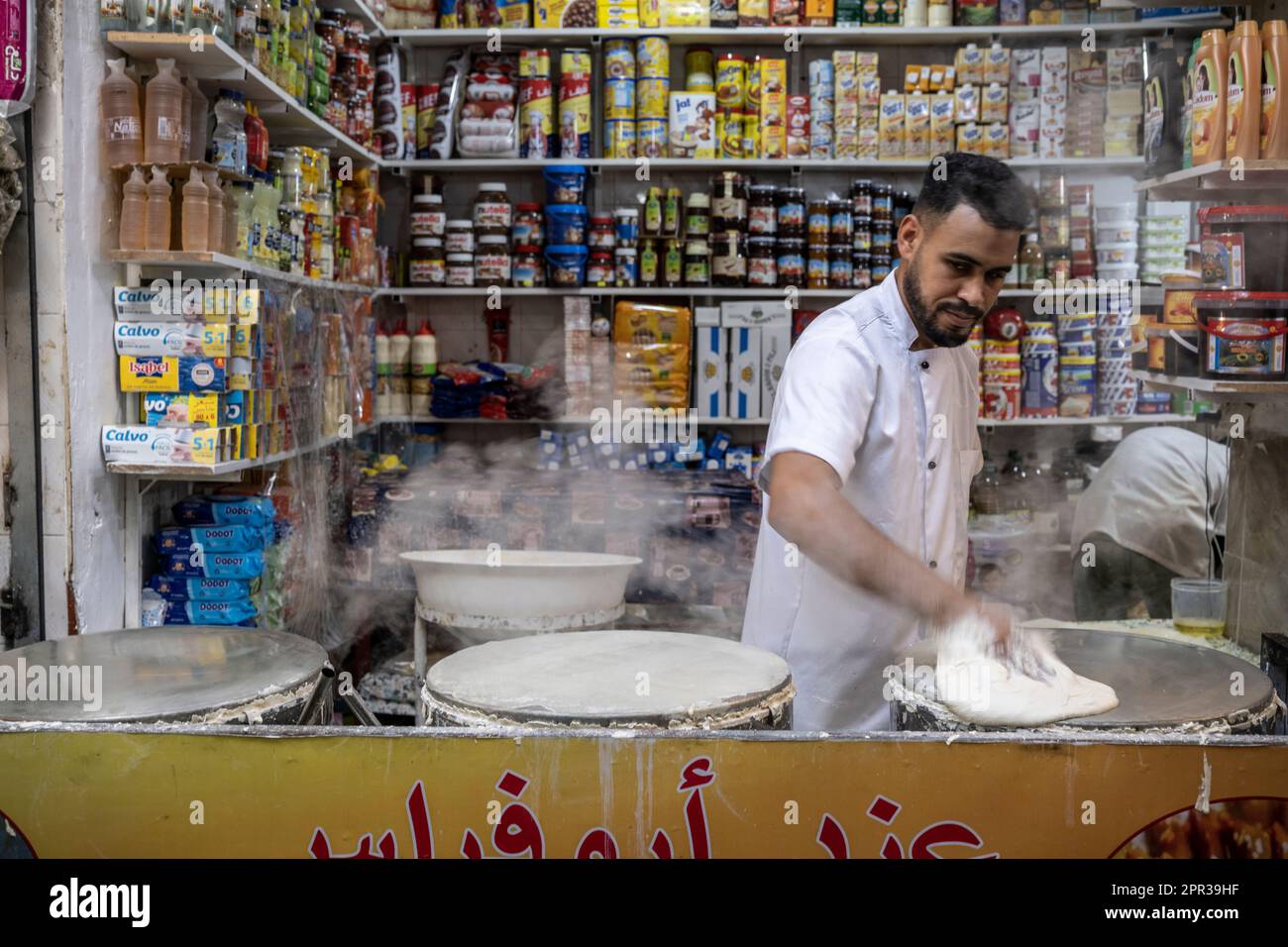Uomo che prepara i fogli di pasta per preparare i dolci tipici marocchini in una bancarella di strada nella medina di Tangeri. Foto Stock