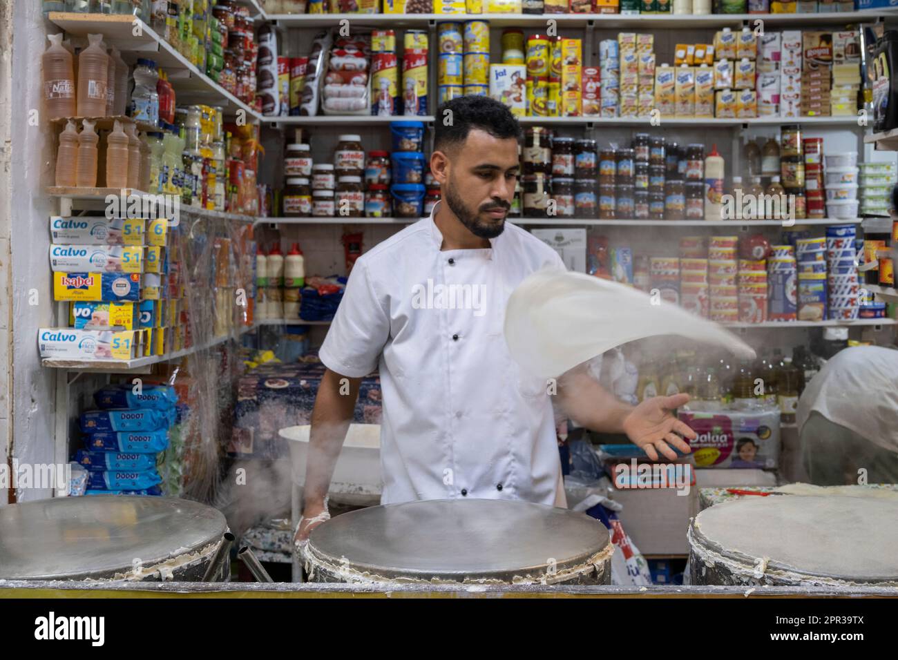 Uomo che prepara i fogli di pasta per preparare i dolci tipici marocchini in una bancarella di strada nella medina di Tangeri. Foto Stock