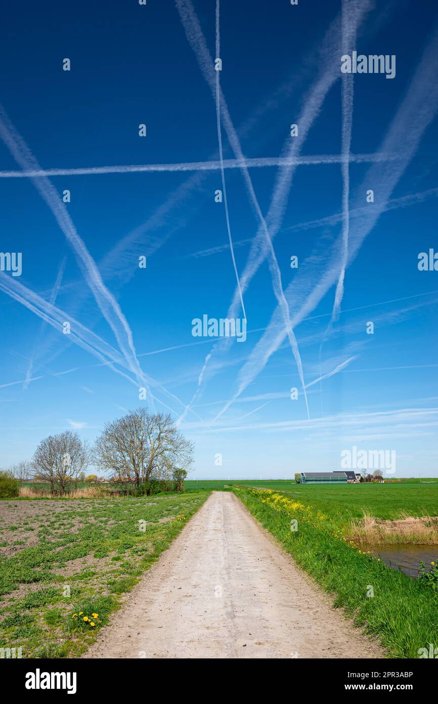 Strada di campagna sotto un cielo pieno di sentieri di vapore Foto Stock