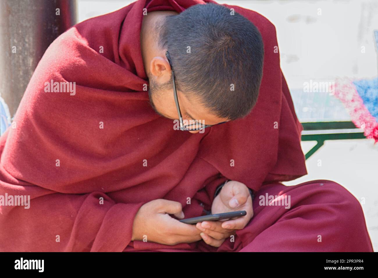 India, Dharamsala - 11 marzo 2018: Monaco buddista (talapoin) con uno smartphone - fusione di tradizione orientale e concetto di rilevanza occidentale, età moderna Foto Stock