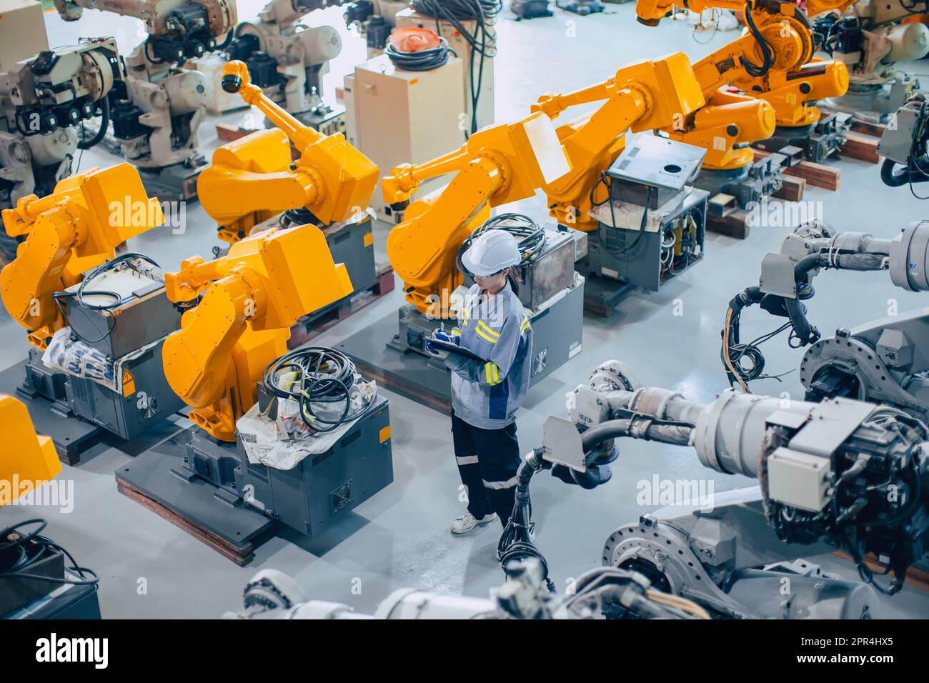 Tecnico addetto al personale che lavora in un grande impianto di assemblaggio delle macchine. lavoro del dipendente con inventario di ispezione del braccio robot della macchina. Foto Stock