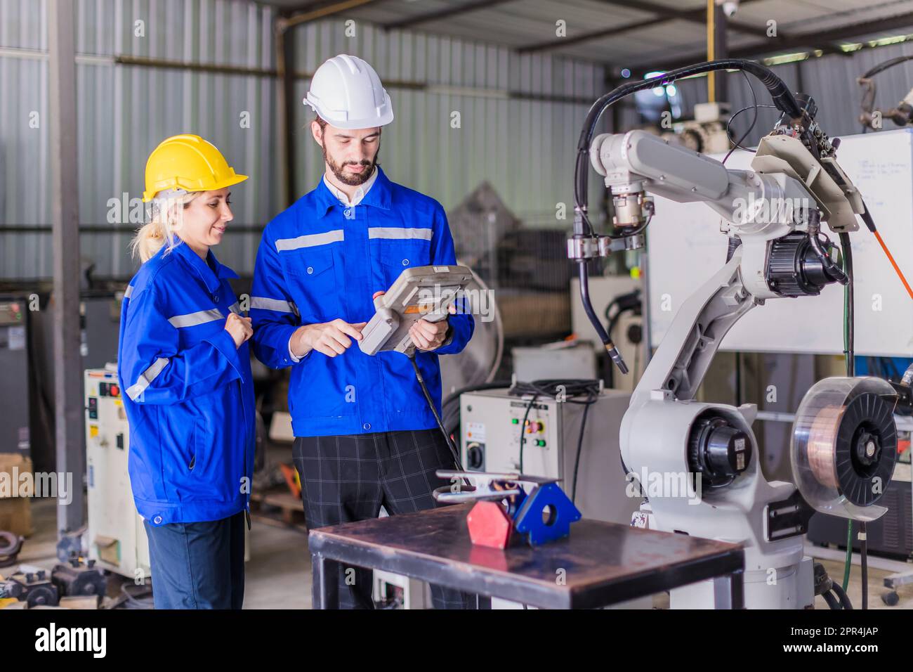 Il team di ingegneri, uomo e donna, che lavorano insieme, aiuta a supportare il lavoro con il servizio di saldatura robot. Foto Stock