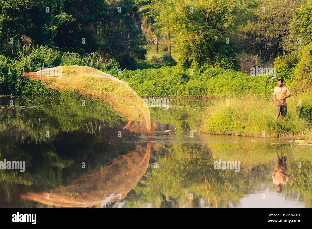 Mangalore, India - 1st Gen, 2023 : un pescatore solista che getta la sua rete nel lago in una mattinata luminosa. Foto Stock