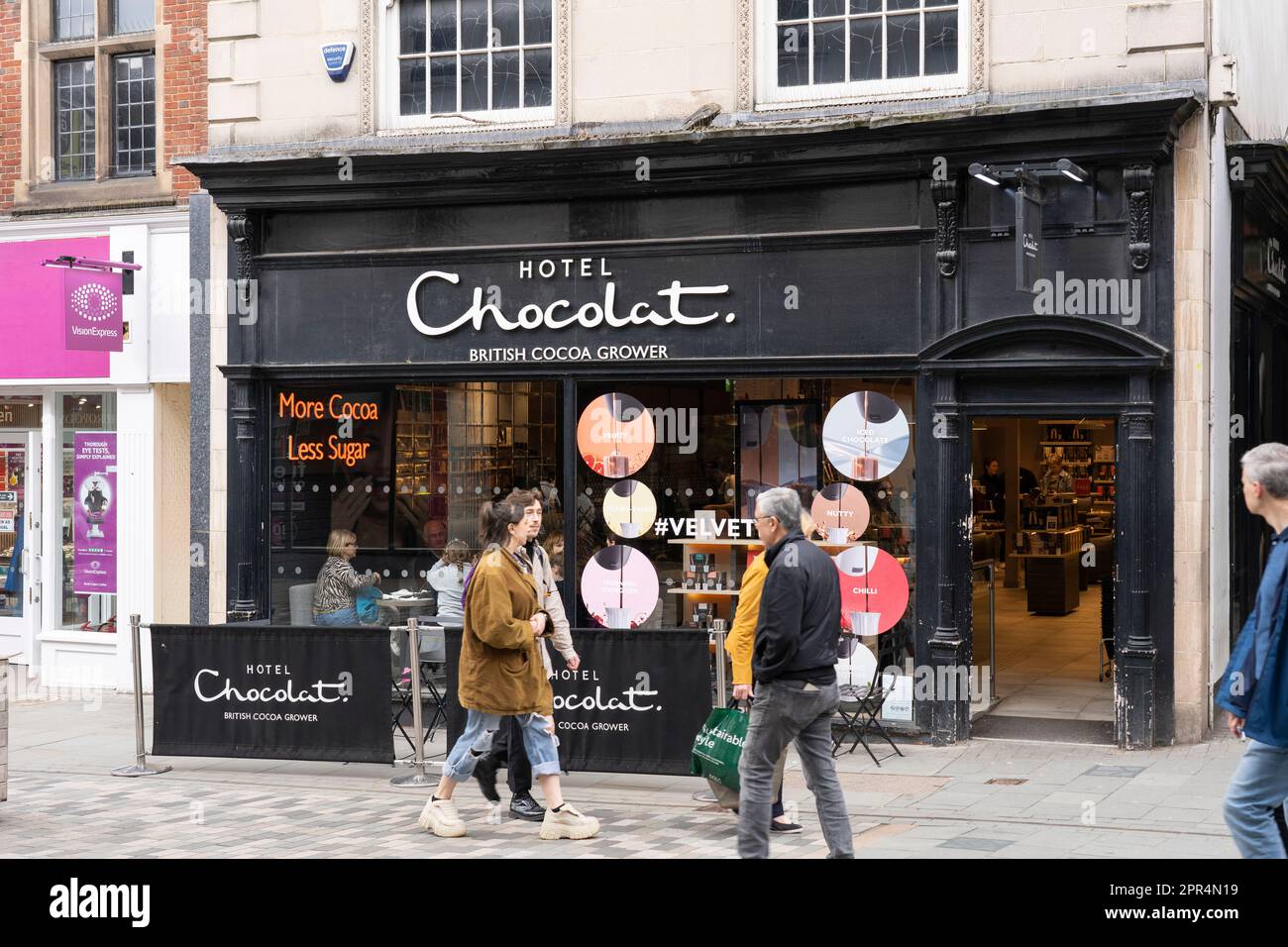 Gli amanti dello shopping sulla Pride Hill pedonale nel centro di Shrewsbury passeggiando davanti all'Hotel Chocolat, un produttore britannico di cacao e cioccolato. REGNO UNITO Foto Stock
