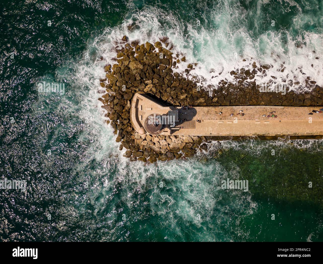 Veduta aerea di un faro e di un frangiflutti che proteggono un porto da un mare accidentato (Chania, Creta, Grecia) Foto Stock