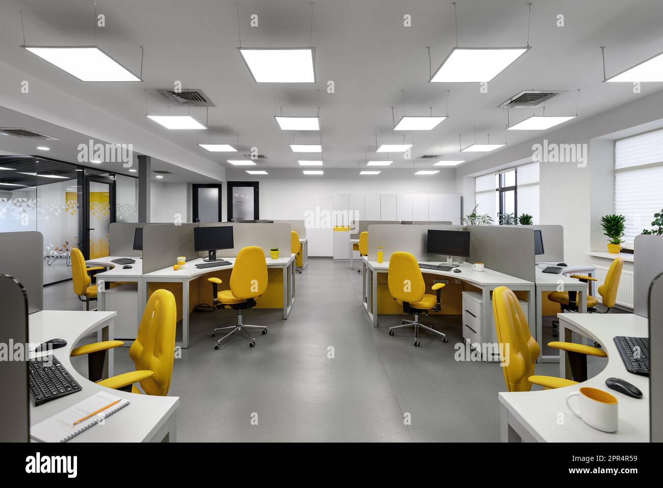 Ufficio IT con postazioni di lavoro per sviluppatori di dipendenti con sedie gialle e computer. Foto Stock