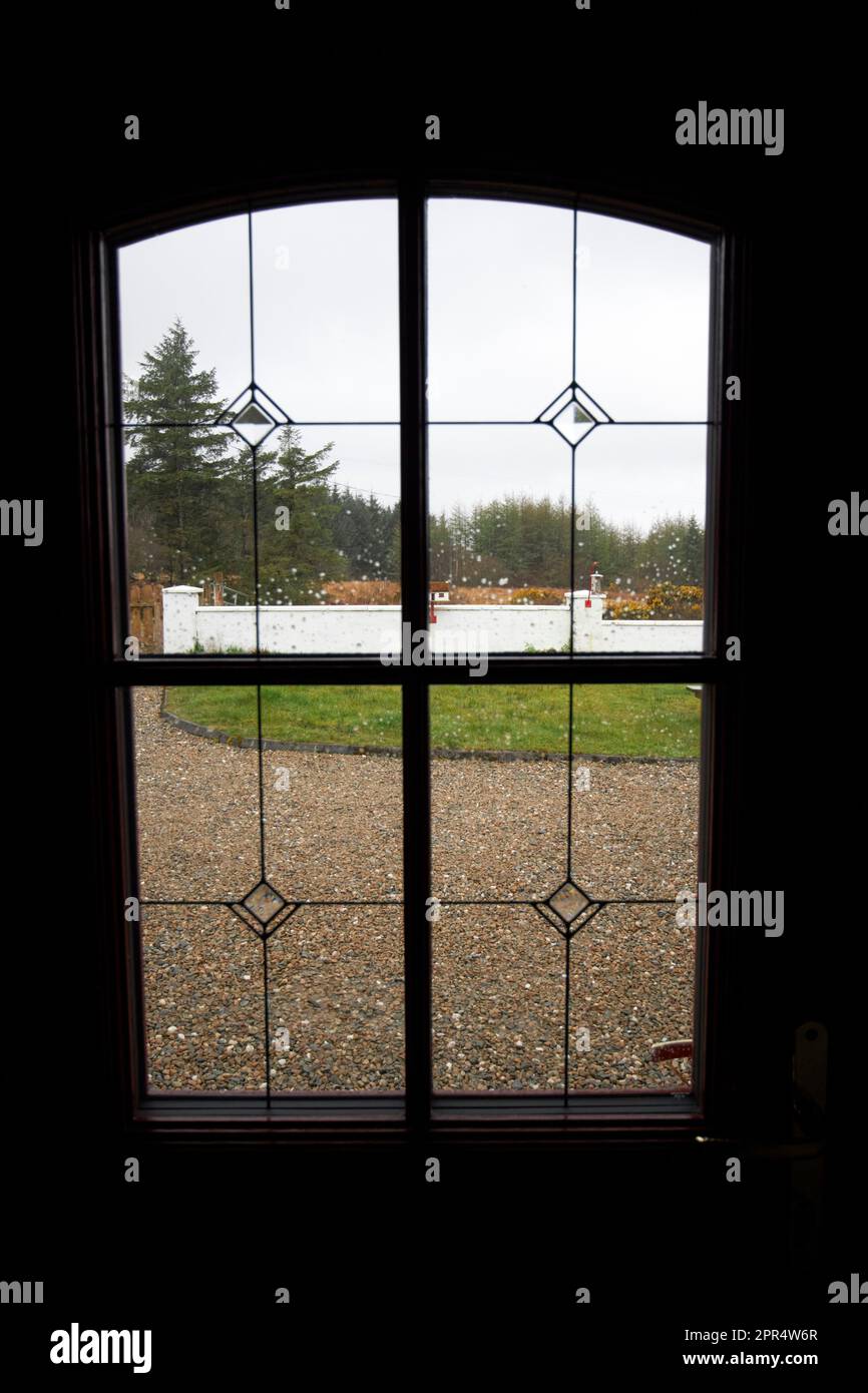 gocce di pioggia sulla finestra di una porta d'ingresso che si affaccia da una casa vacanze cottage nella contea donegal repubblica d'irlanda Foto Stock