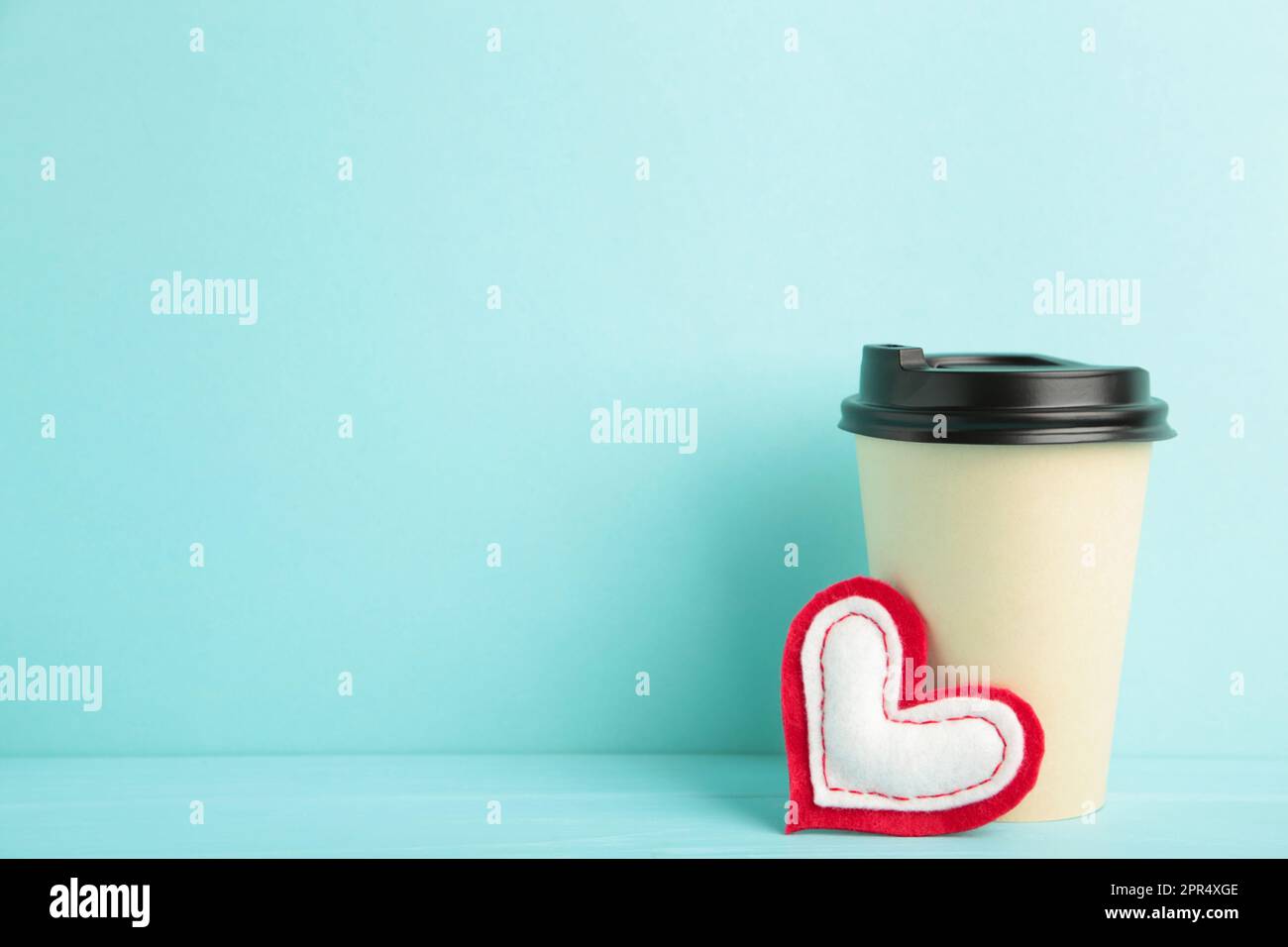 Cuore rosso con tazza da caffè di carta beige su blu. Vista dall'alto Foto Stock
