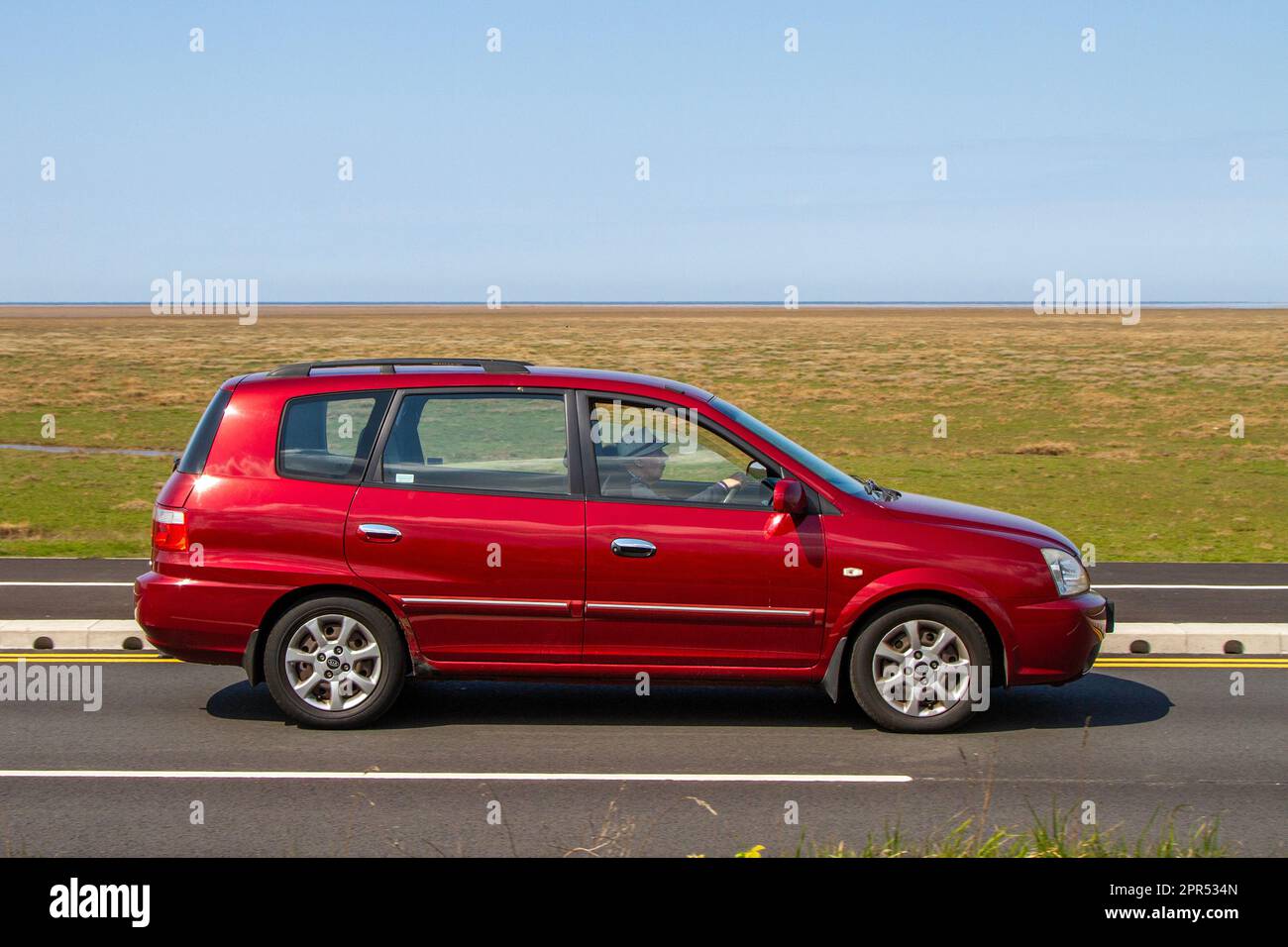 Vista laterale di 2005 KIA Carens CRDI LxCrdi 111 Red Car Medium MPV Diesel 1991 cc; viaggiando sul lungomare Marine Drive, Southport, Regno Unito Foto Stock