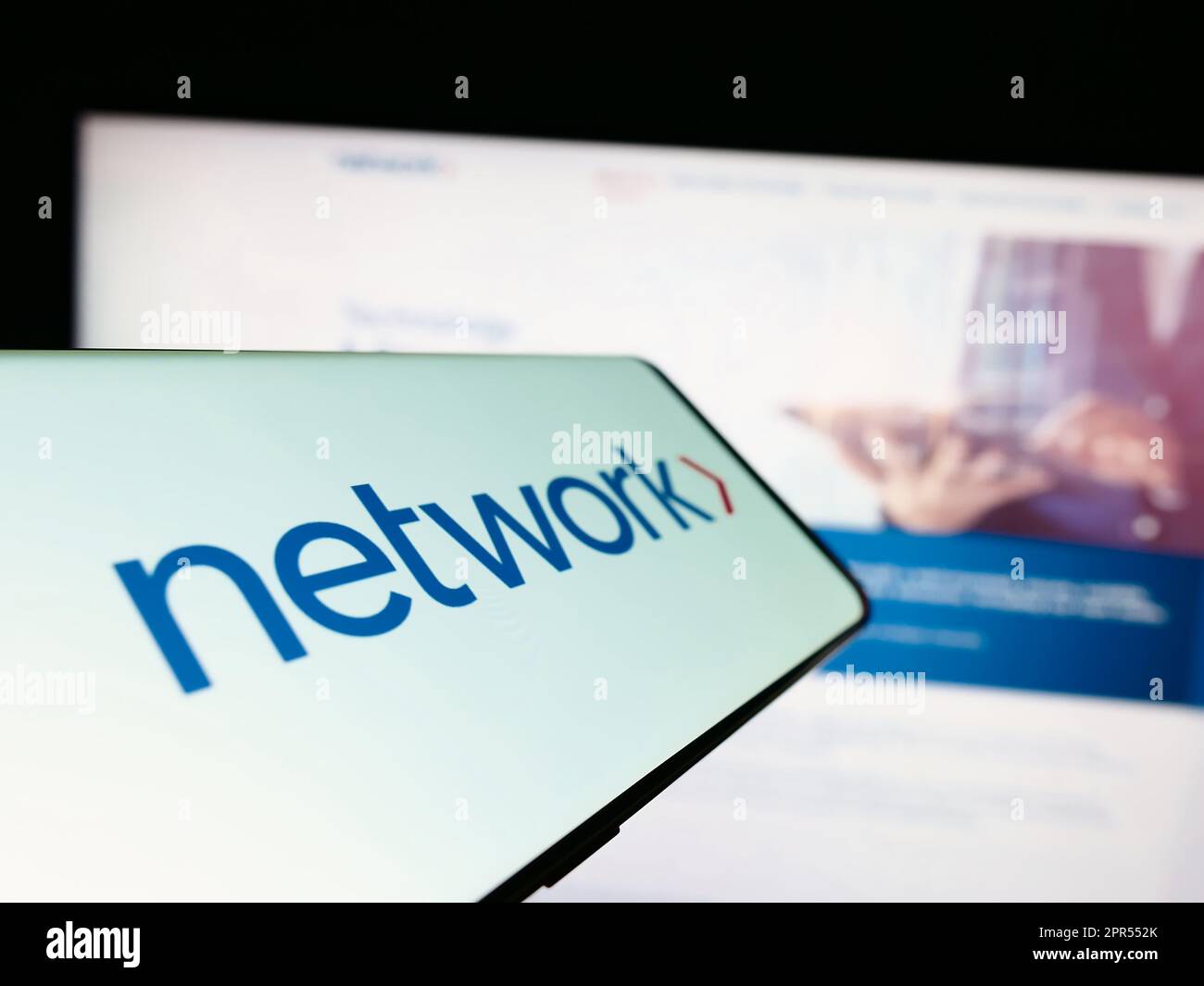 Telefono cellulare con il logo della società Network International Holdings plc sullo schermo di fronte al sito web. Messa a fuoco al centro a sinistra del display del telefono. Foto Stock