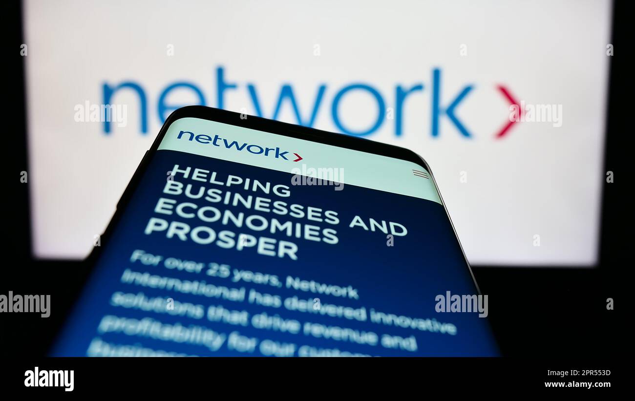 Smartphone con pagina Web della società Network International Holdings plc sullo schermo di fronte al logo aziendale. Messa a fuoco in alto a sinistra del display del telefono. Foto Stock
