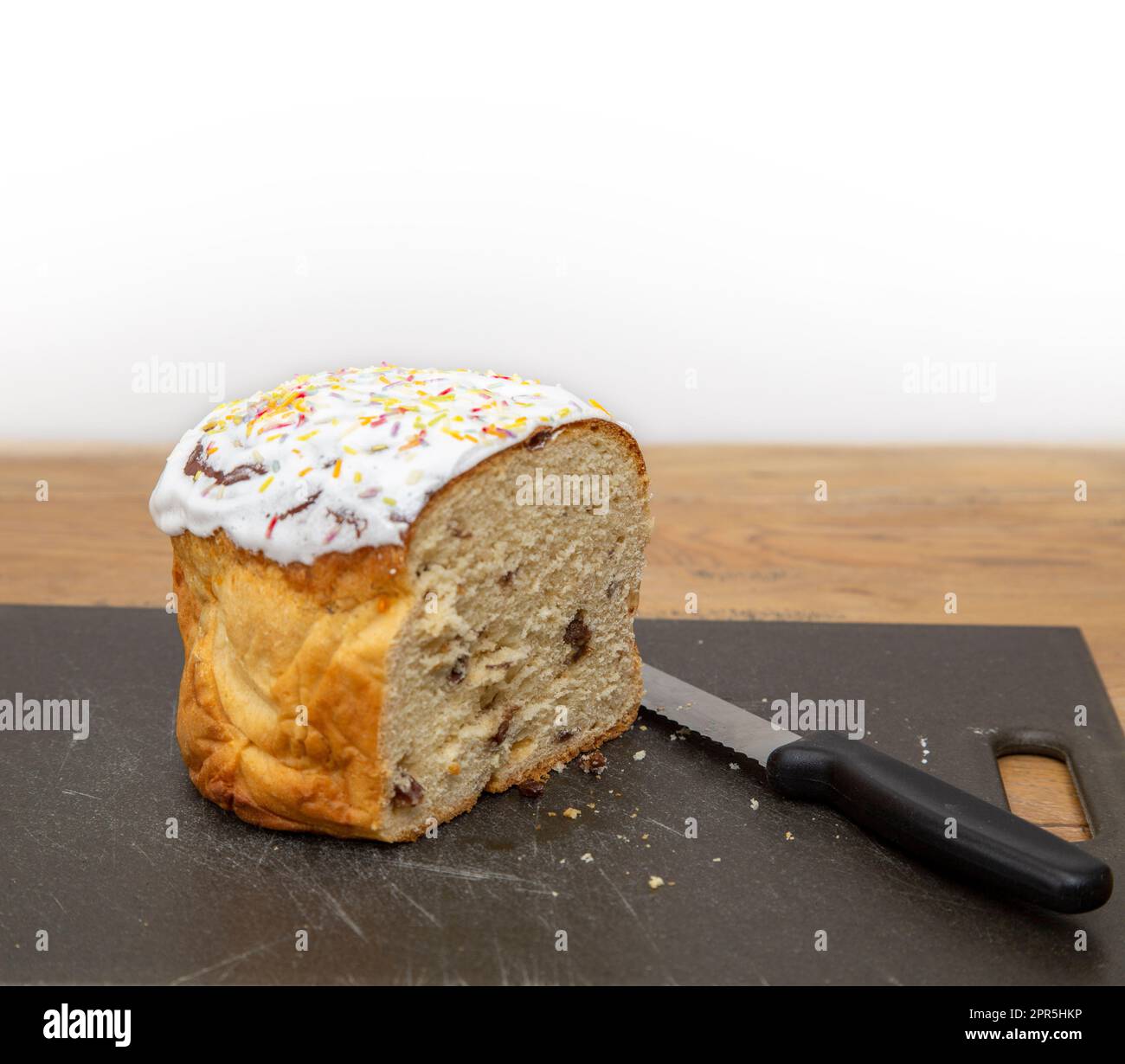 Cibo tradizionale ucraino di Pasqua, Paska, pane di frutta ghiacciato. Anche Kulich nella tradizione russa. Coltello per pane sul tritare. Foto Stock