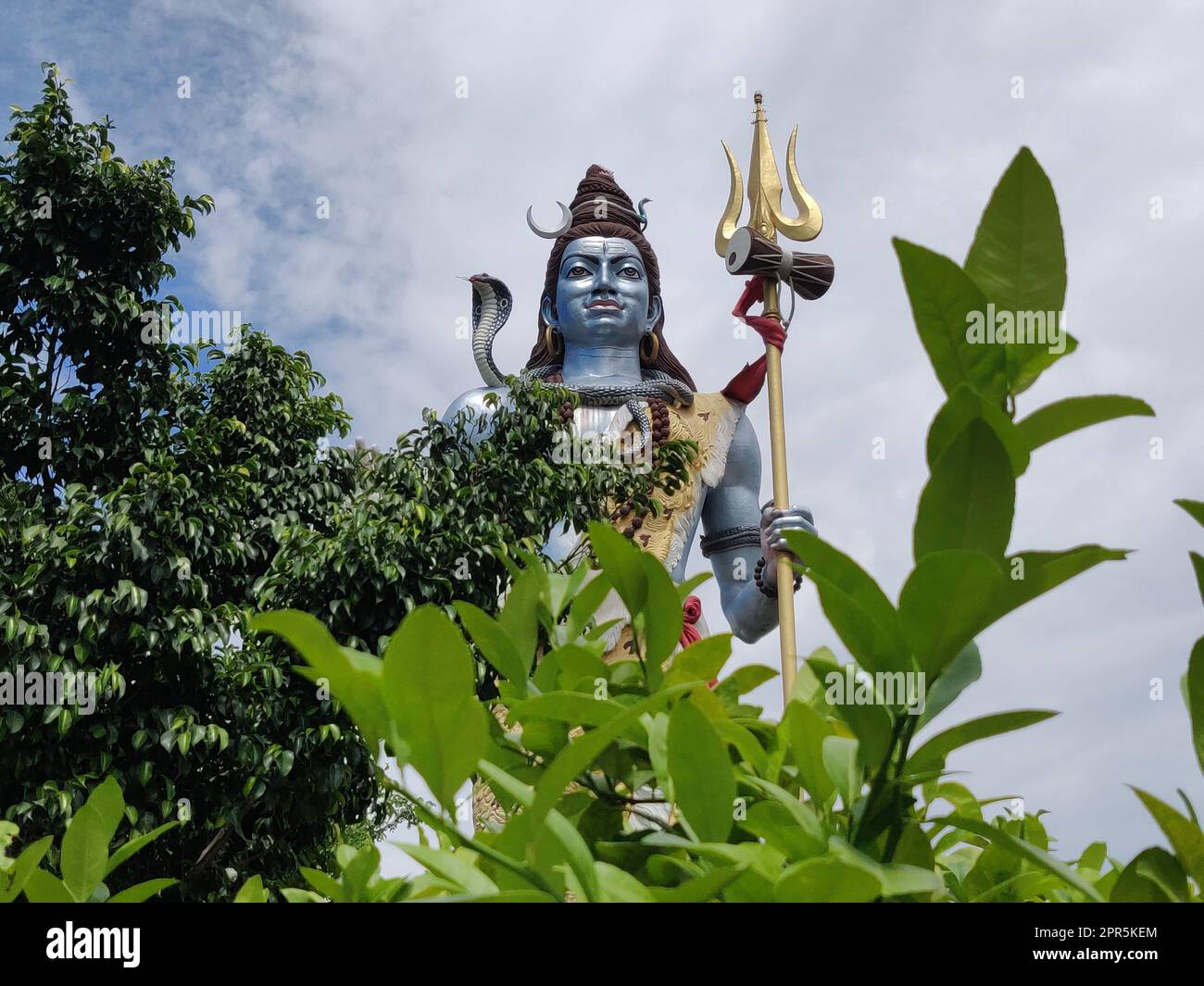 Un primo piano di una statua Hindu Lord Shiva in India con un cielo blu nuvoloso sullo sfondo Foto Stock