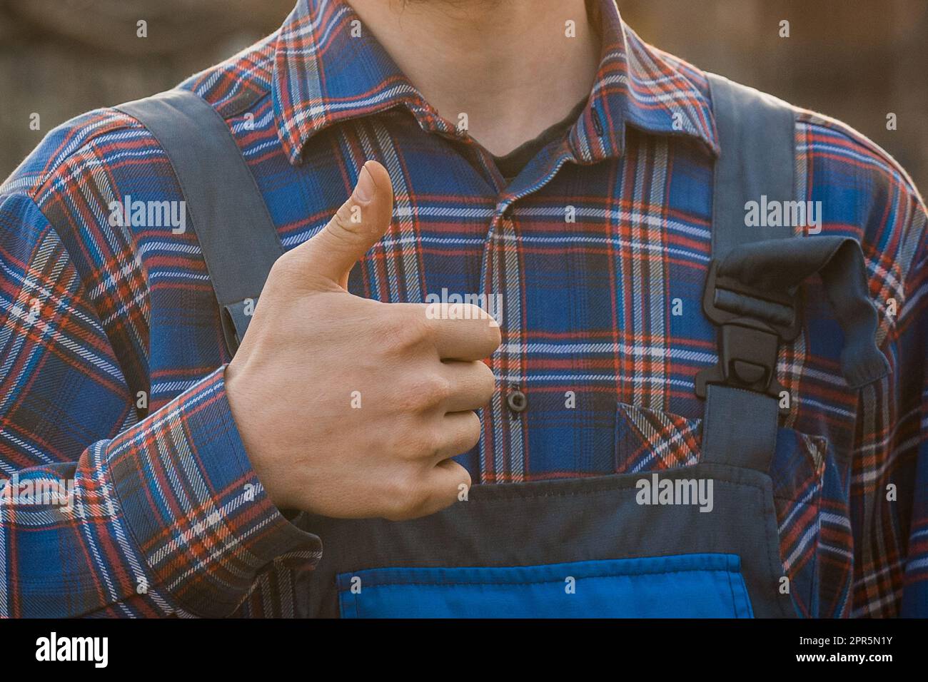 Contadino uomo rurale primo piano con camicia e tute che mostrano un gesto fresco con il dito della mano. Foto Stock