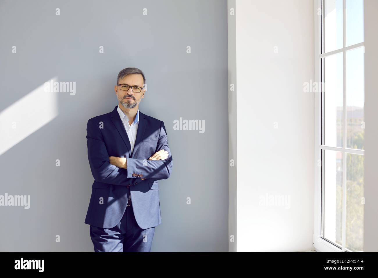 Uomo d'affari di mezza età seduto al muro con le mani ripiegate Foto Stock