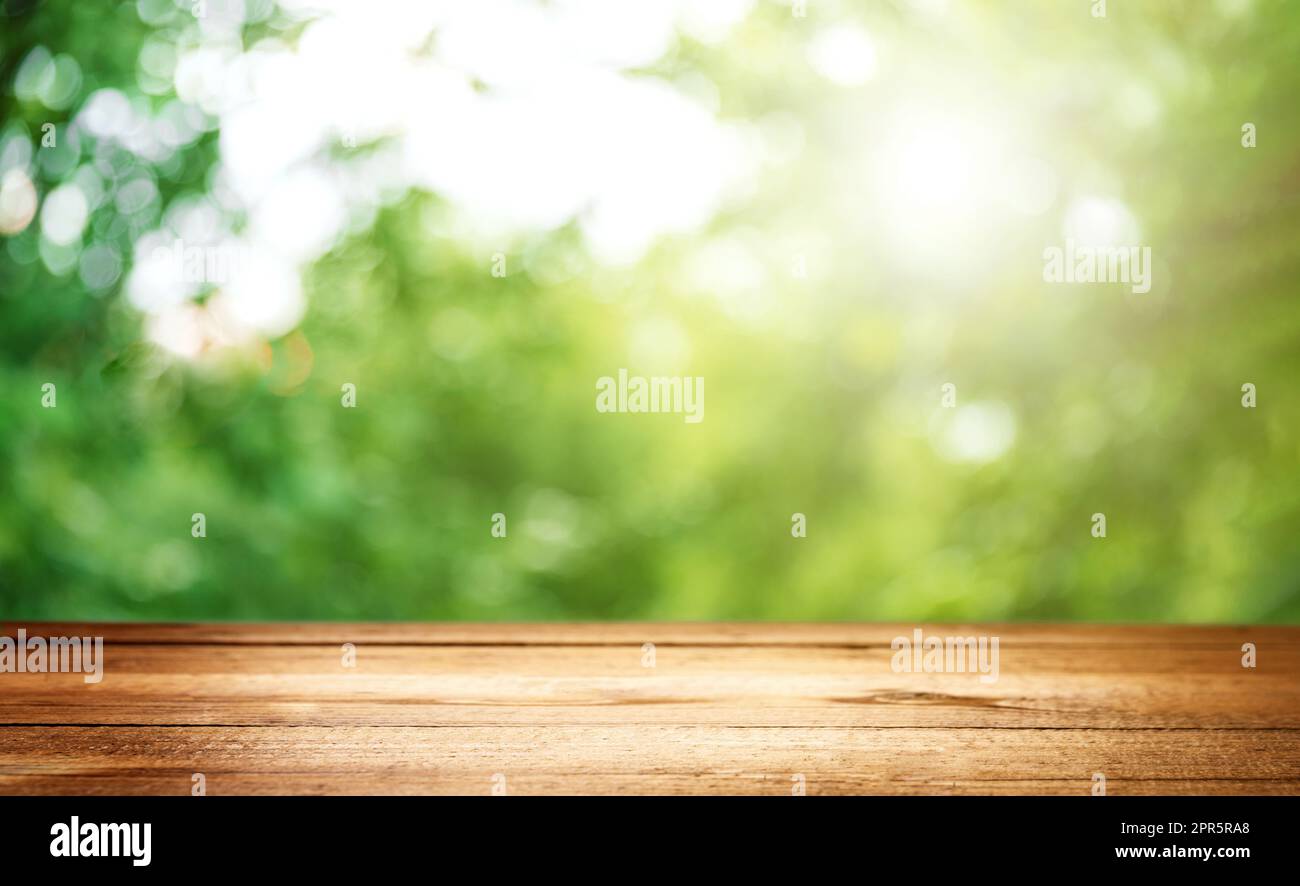 Tavola, ponte o tavolo vuoti in legno con sfondo verde sfocato Foto Stock