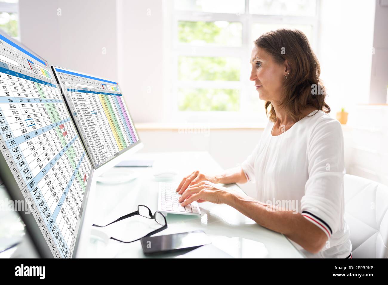 Foglio di calcolo analista dipendente che utilizza monitor computer Foto Stock