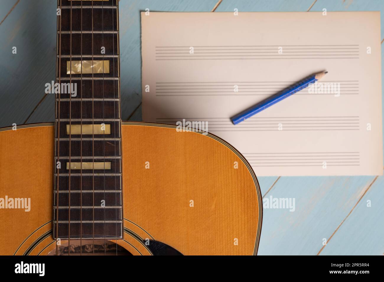 Scena di registrazione musicale con chitarra, foglio di musica vuoto e matita su tavolo di legno Foto Stock