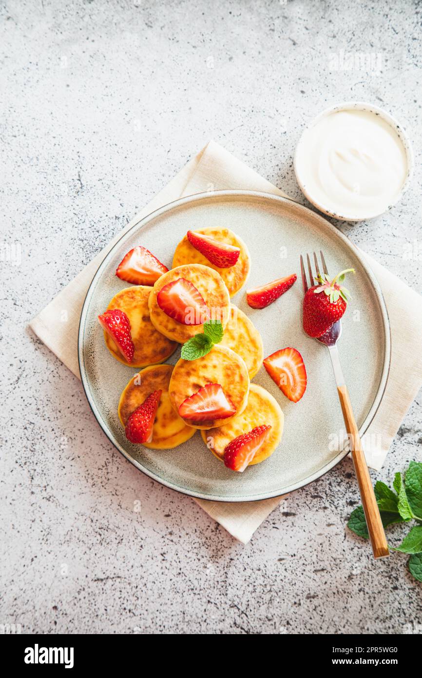 Frittelle di formaggio cottage, frittelle di ricotta o scironiki con menta e fragole. Sana e deliziosa colazione mattutina. Foto Stock