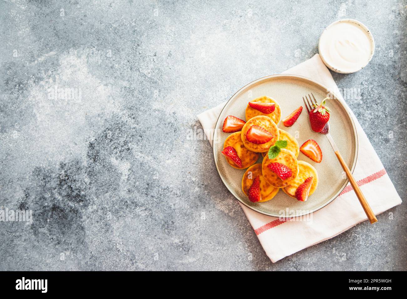 Frittelle di formaggio cottage, frittelle di ricotta o scironiki con menta e fragole. Sana e deliziosa colazione mattutina. Foto Stock