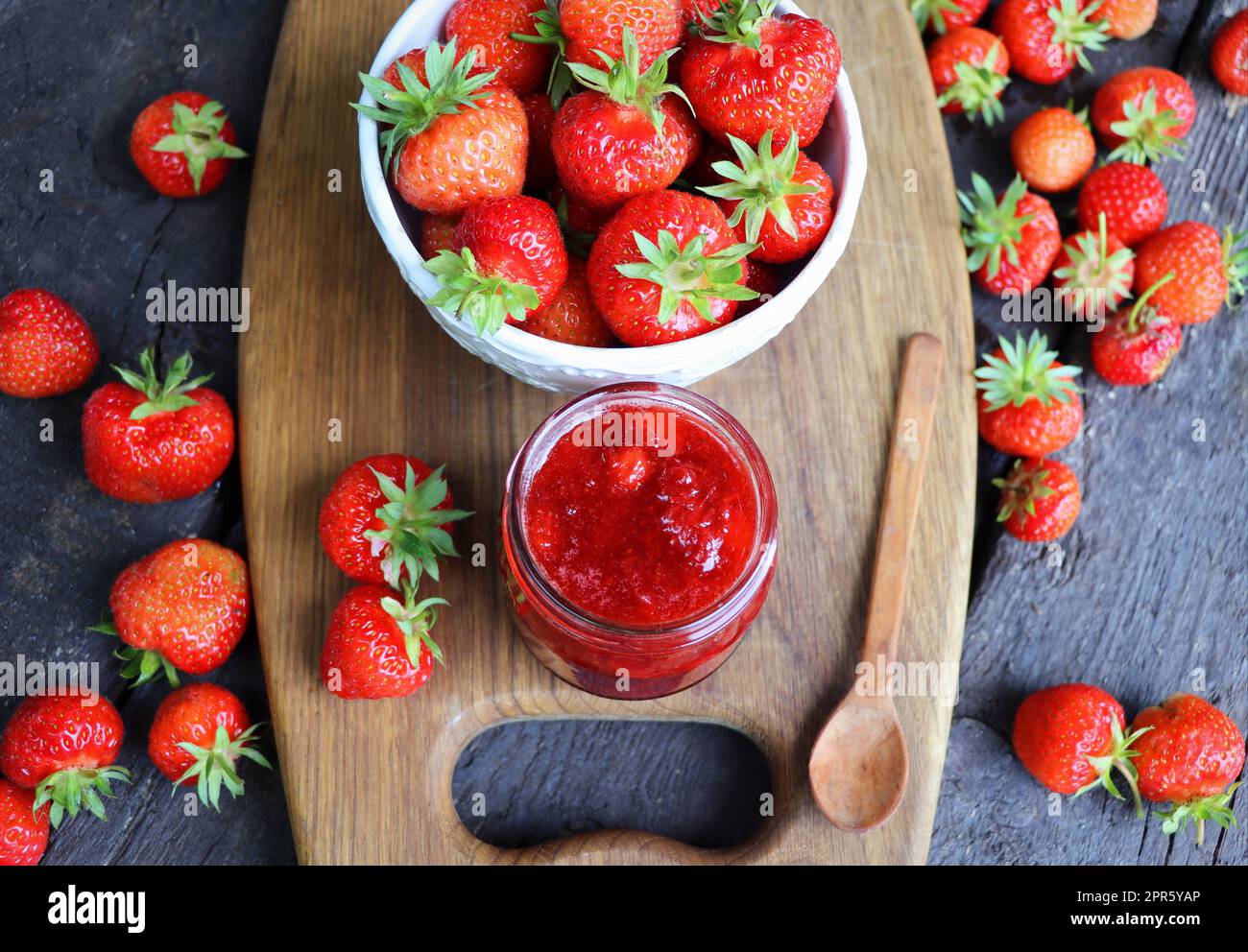 Marmellata di fragole fatta in casa o marmellata nel vaso di vetro e le fragole fresche sul tavolo rustico in legno Foto Stock