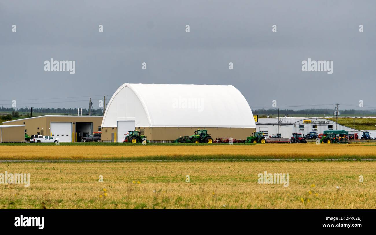 La società di riparazione di attrezzature agricole Ebert Welding Ltd., in New Liskeard, Temiskaming Shores, Ontario, Canada, con campi di grano dorato in primo piano Foto Stock
