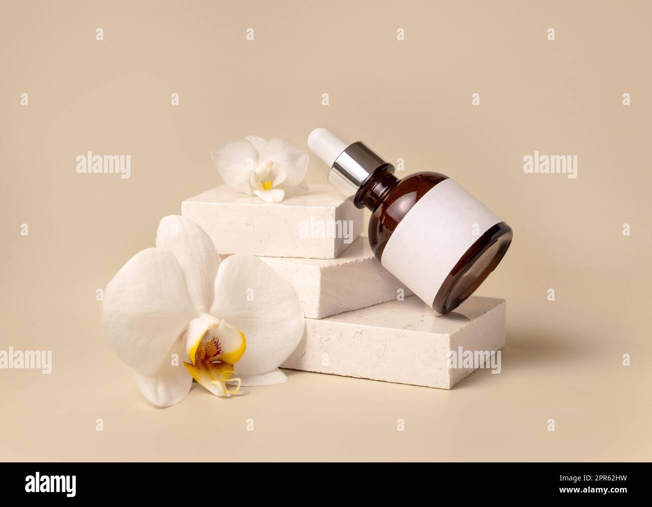 Bottiglia di vetro contagocce su pietra vicino a fiori di orchidea bianchi di colore giallo chiaro, Mockup cosmetico Foto Stock