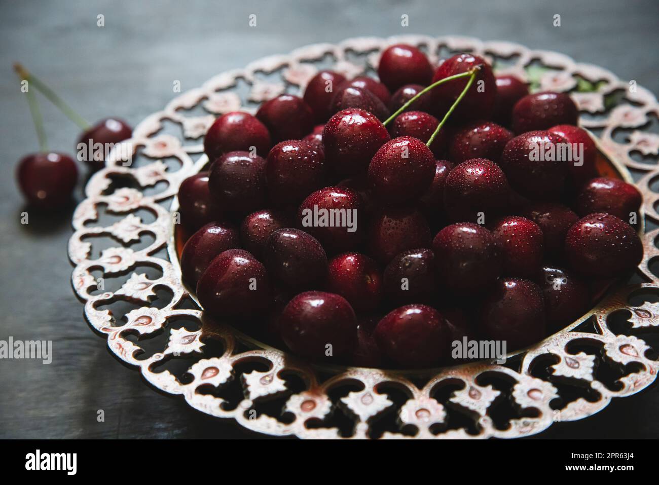 Composizione delle ciliegie dolci su un piatto con gocce d'acqua. Concetto di estate e raccolto. Ciliegio macro. Vegano, vegetariano, crudo Foto Stock