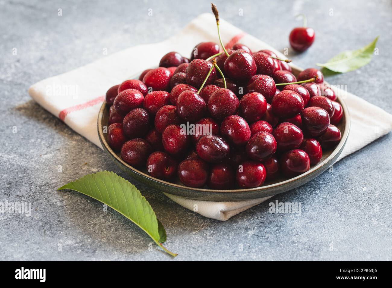 Composizione delle ciliegie dolci su un piatto con gocce d'acqua. Concetto di estate e raccolto. Ciliegio macro. Vegano, vegetariano, crudo Foto Stock