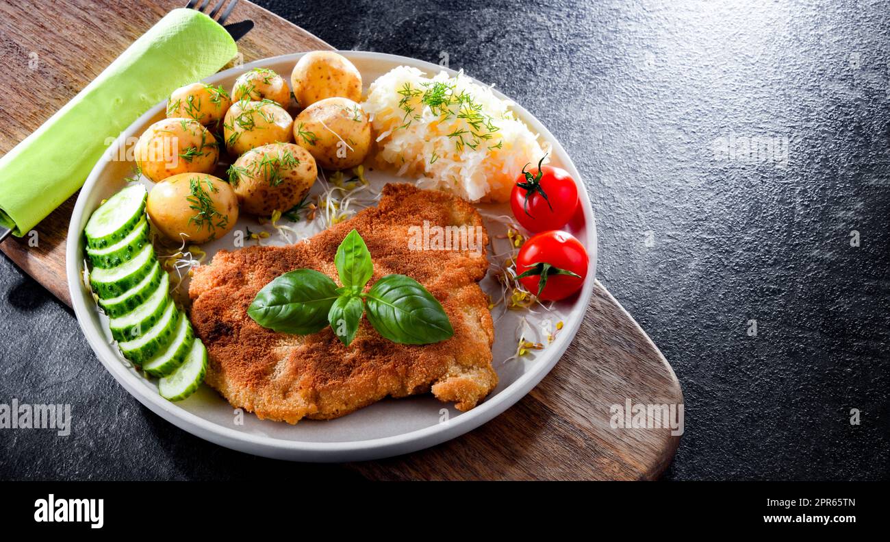Cotoletta di maiale ricoperta di pangrattato con patate e cavolo Foto Stock
