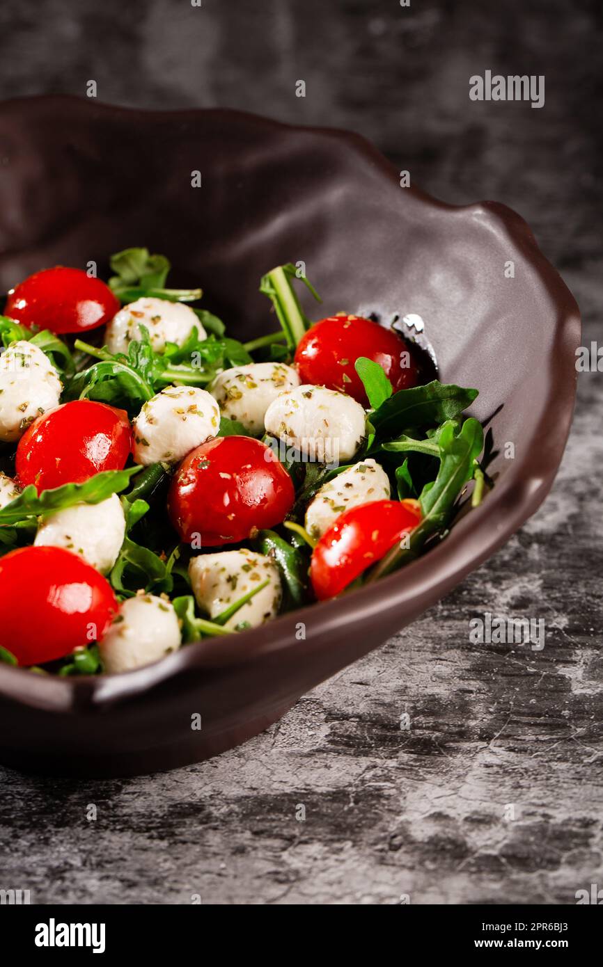 Insalata caprese. Rucola fresca, pomodori ciliegini, mini mozzarella succosa e un condimento di origano e olio d'oliva Foto Stock