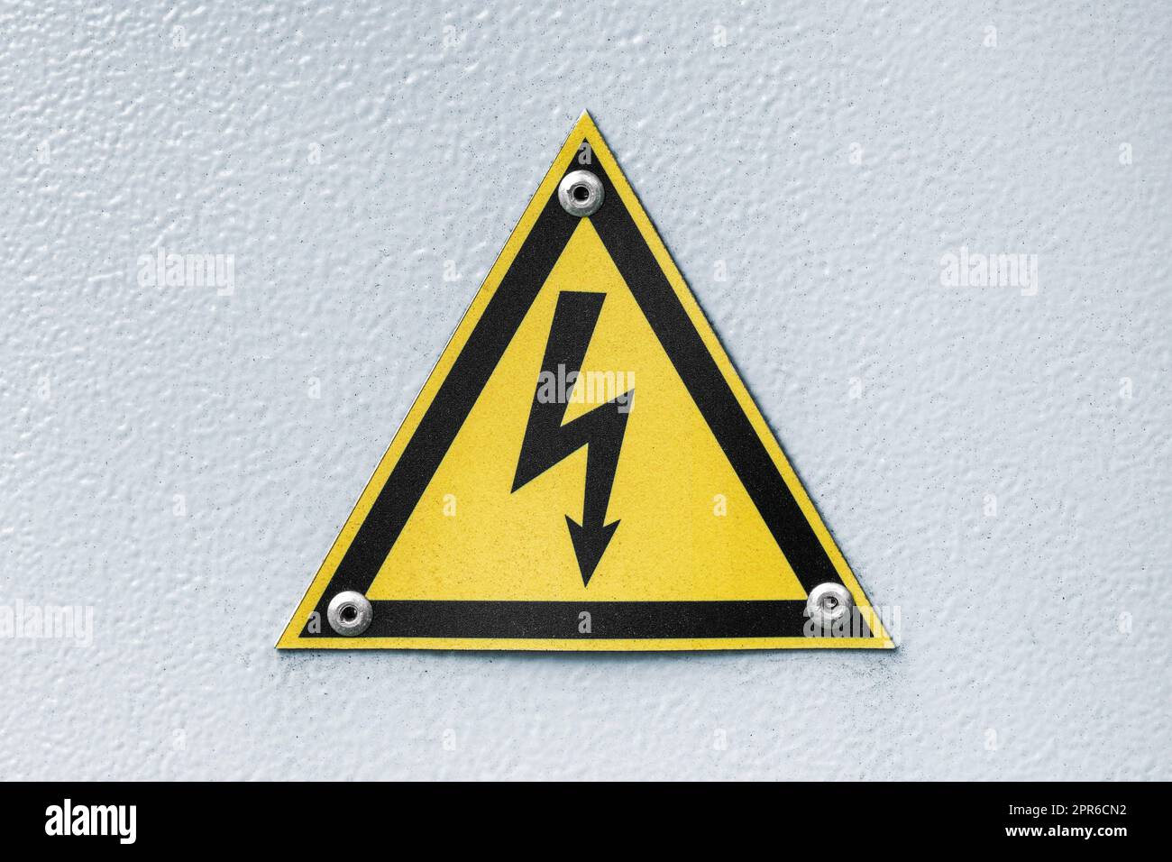 Segno giallo triangolare di tensione elettrica pericolosa Foto Stock