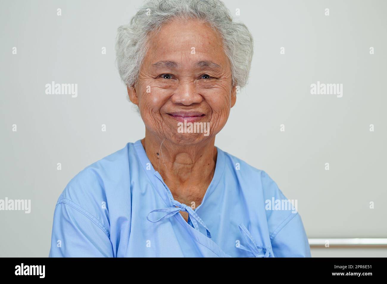 Donna anziana asiatica paziente seduto e sorridere faccia con felice a letto in ospedale. Foto Stock